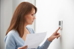 Woman Adjusting Thermostat for heat pump